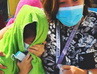 A Philippines Department of Social Welfare and Development (DSWD) social worker comforts and shields a girl from the media 